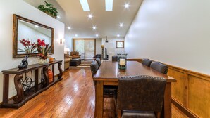A spacious dining area with a wooden table and chairs, a console table with decorative items, and a large mirror on the wall. - Bright, Newly Remodeled 2/2 w/ Garage & Laundry! (Mammoth Lakes)