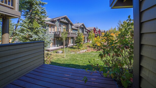 A residential area with a wooden deck, houses with balconies, and a clear blue sky. - Bright, Newly Remodeled 2/2 w/ Garage & Laundry! (Mammoth Lakes)