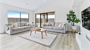 A spacious living room with two grey sofas, a wooden coffee table, and a large window providing a view of the outdoors.