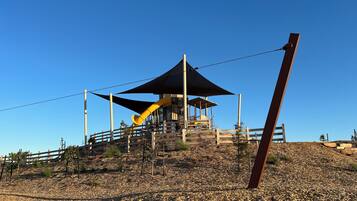 A playground with a slide and a shaded pavilion on a hill.