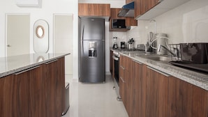 Eine moderne Küche mit Holzausstattung, einem Edelstahlkühlschrank, einem Einbauofen und einer Kaffeemaschine.