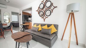 Ein modernes Wohnzimmer mit grauem Sofa, Couchtisch aus Holz und einer Stehlampe.