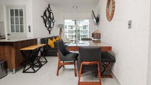 Eine moderne Küche mit einer Holzausziehtheke, einem Essbereich mit einem Glastisch und einer Couch mit gelben Kissen.