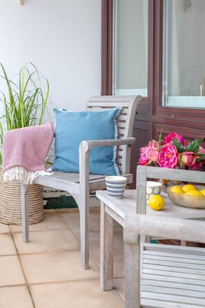 Eine hölzerne Bank mit blauer Polsterung, einem Korbwannenaufsatz und einem Tisch mit Zitronen und Blumen.
