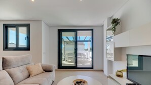 A modern living room with a sofa, a coffee table with a bowl, a TV, and a sliding glass door leading to an outdoor patio.