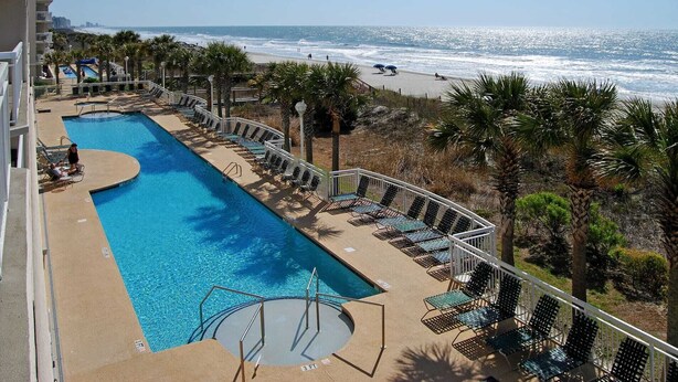 A pool with a view of the beach and ocean.