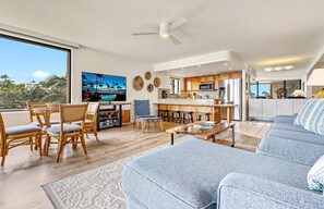 Een moderne woonkamer met een grote televisie, eethoek, keuken en een balkon met uitzicht.