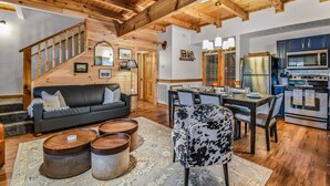 Amplia sala de estar con escalera de madera, mesa de comedor y cocina equipada con electrodomésticos modernos.