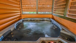 Un jacuzzi con vistas a zonas verdes, rodeado de paredes de madera.