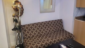 A room with a patterned sofa, a decorative lamp, and a framed mirror on the wall. - Elegant Modern 1 Bedroom Apt in Toronto North York (Toronto)
