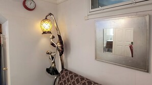 A room with a clock, a wall-mounted lamp, a mirror, and a door with a handle. - Elegant Modern 1 Bedroom Apt in Toronto North York (Toronto)