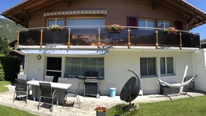 A two-story chalet with a balcony, outdoor seating, and a barbecue area. - Cosy apartment for 4 people with WIFI, TV and balcony (Fuhre)