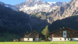 A mountain landscape with a house featuring a staircase and a second building with a white facade. - Cosy apartment for 4 people with WIFI, TV and balcony (Fuhre)