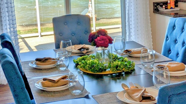 Un coin repas avec une table dressée pour deux personnes, donnant sur une étendue d’eau.