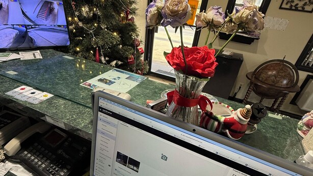 A desk with a computer, keyboard, and calculator. A Christmas tree is in the background. - CourtesyStay (Mansfield)