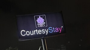 A CourtesyStay sign at night with a Texaco gas station in the background. - CourtesyStay (Mansfield)