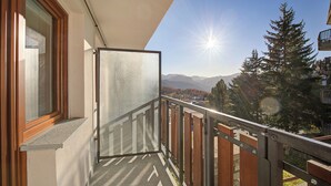 A balcony with a view of mountains and trees.