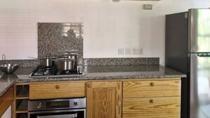 Una cucina con piani in granito, mobili in legno, un fornello, un forno e un frigorifero in acciaio inossidabile.