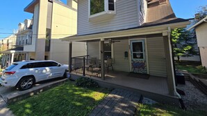A two-story house with a covered porch, a garage, and a small garden area. - Stand Alone Studio, Free Off Street Parking, Walkable 2 Downtown, Beautiful Area (Cincinnati)