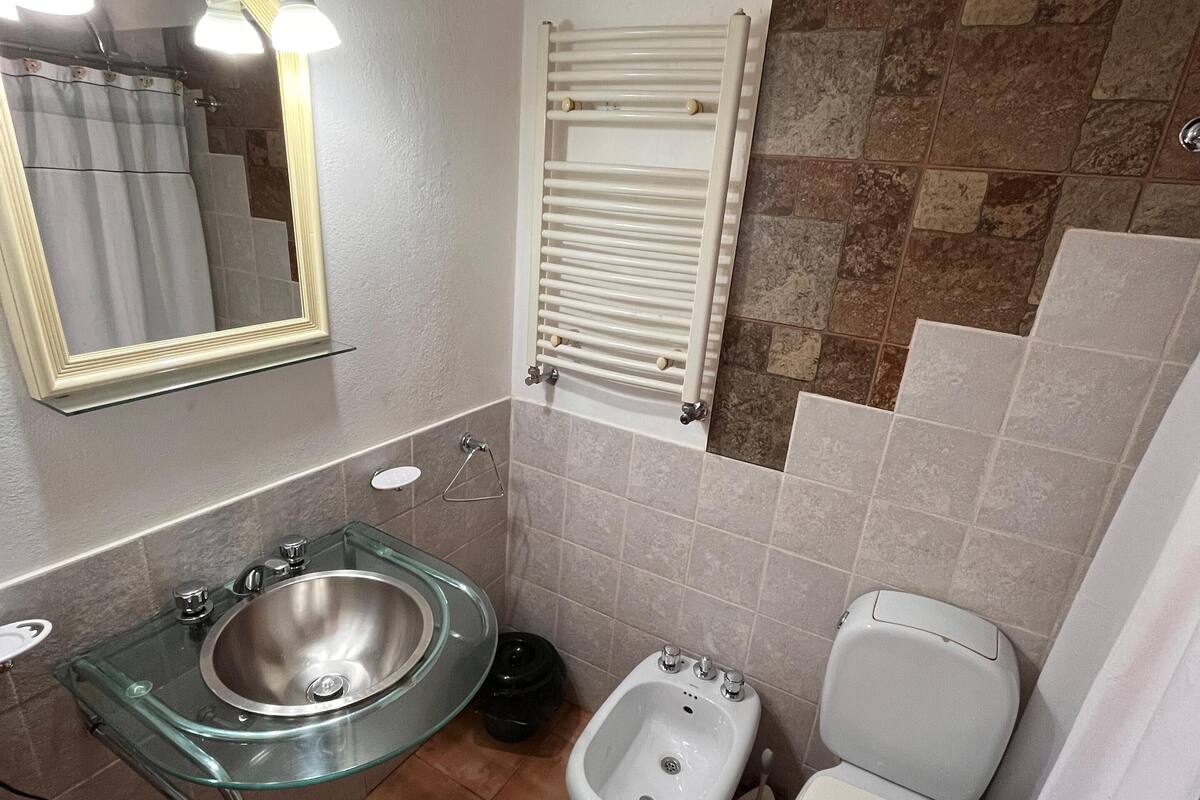 A bathroom with a glass sink, a bidet, a toilet, and a towel rack.