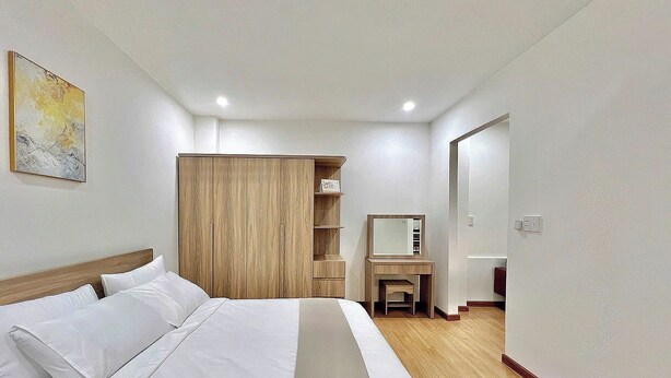 Ein Hotelzimmer mit einem Bett, einem Holzschrank, einem Schreibtisch mit Spiegel und einer kleinen Sitzecke.