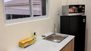 Eine kleine Küche mit Spüle, Mikrowelle und Kühlschrank.