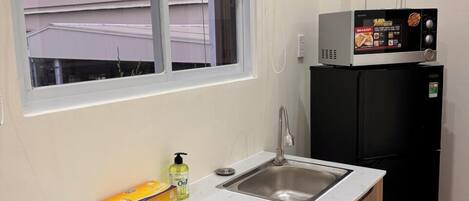 A compact kitchen with a sink, a microwave, and a refrigerator.