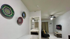 Ein modernes Hotelzimmer mit einem Bett, einer Couch, einem Fernseher und dekorativen Tellern an der Wand.