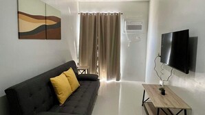 Ein modernes Wohnzimmer mit einem dunklen Sofa, einem Holztisch und einem Flachbildfernseher.