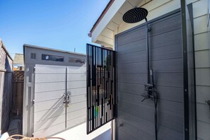 A modern outdoor shower enclosure with a metal gate, a hose, and a handheld showerhead. - Modern Coastal Escape - walking distance to beach! (Santa Cruz)