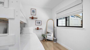 A compact, modern bedroom with a bunk bed, a bedside table with a lamp, a mirror, and a window with blinds. - Modern Coastal Escape - walking distance to beach! (Santa Cruz)