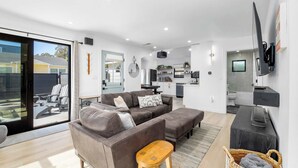 A modern living space with a sofa set, a dining area, a kitchen, and a TV mounted on the wall. - Modern Coastal Escape - walking distance to beach! (Santa Cruz)