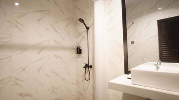 Un baño con un lavabo blanco, un espejo y una ducha con cabezal de ducha manual.
