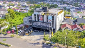 Un edificio moderno con un gran cartel digital, un estacionamiento y una calle con paso de peatones.