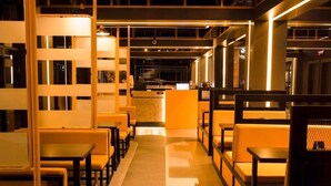 Un restaurante moderno con una barra central, cabinas y suelo estampado.