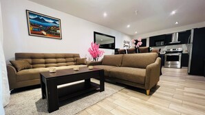 A modern living room with two sofas, a coffee table, and a kitchen area with a stove and refrigerator.