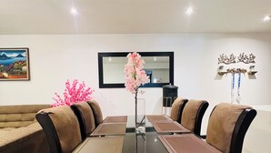 A dining area with a rectangular table, brown cushioned chairs, and a vase with pink flowers.