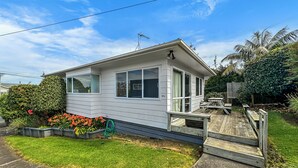 Een gelijkvloers huis met een veranda, een klein terras en een verzorgde tuin.