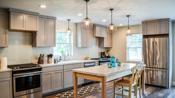 A modern kitchen with stainless steel appliances, wooden cabinets, and pendant lighting. - We Connect Co-Living (St. Louis Park)