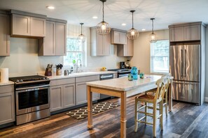 A modern kitchen with stainless steel appliances, wooden cabinets, and pendant lighting. - We Connect Co-Living (St. Louis Park)