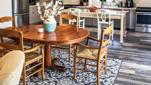 A modern kitchen with a central island, wooden chairs, and a chandelier. - We Connect Co-Living (St. Louis Park)