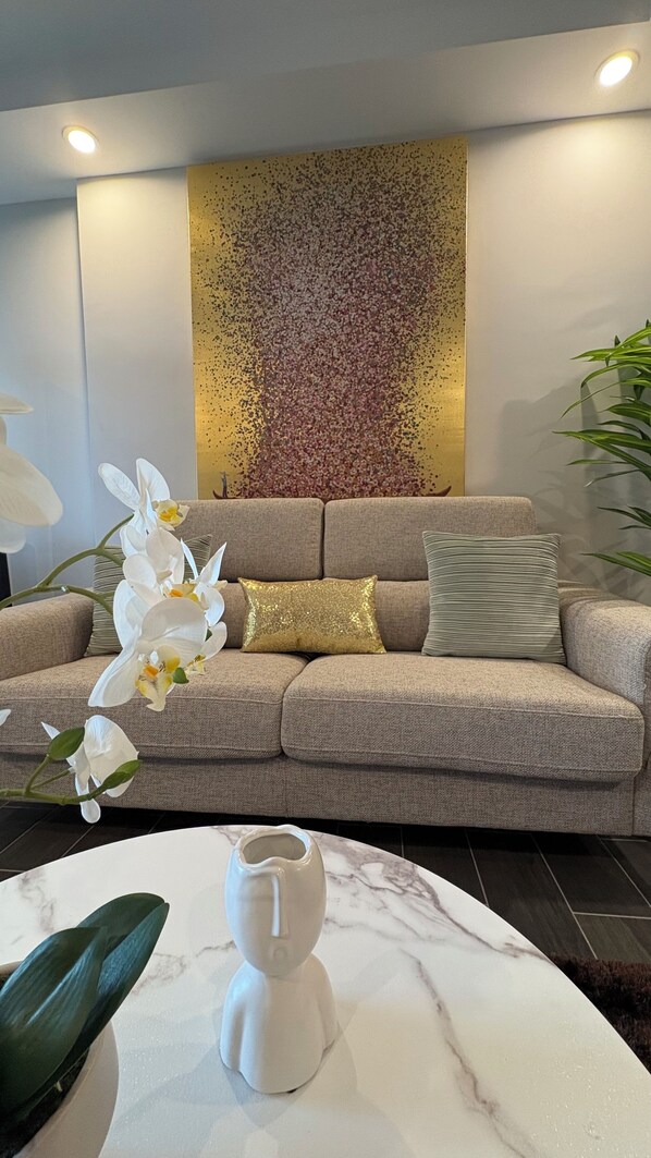 A modern living room with a beige sofa, a decorative wall, and a marble coffee table.