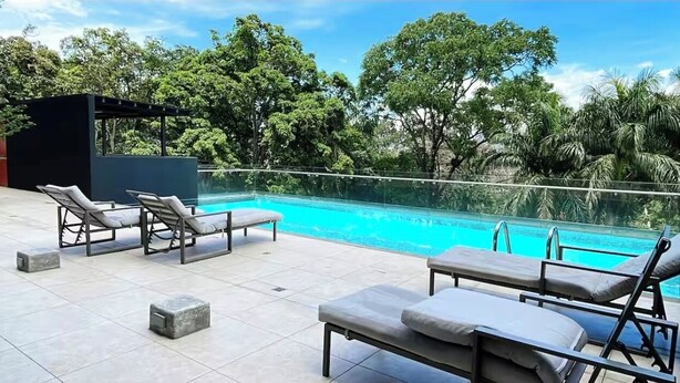 A rooftop pool area with lounge chairs and a pergola. - Cozy Apartment 10 min to Airport Be Cariari Condo new (Ulloa)
