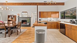 Une cuisine moderne avec des meubles en bois, un lave-vaisselle et un coin repas comprenant une table et des chaises en bois.