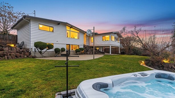 Une maison à deux étages avec un jacuzzi bien visible au premier plan.