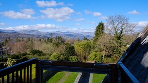 A balcony with a view of a mountainous landscape, a wooden railing, and a clear sky. - Oakland West - Windermere, Sleeps 14 (Windermere)