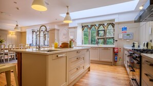 A spacious kitchen with a large island, modern appliances, and a view through the window. - Oakland West - Windermere, Sleeps 14 (Windermere)