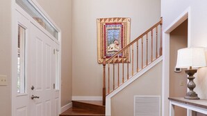 Una escalera con barandillas de madera y un tapete estampado que lleva a una puerta con ventanal.