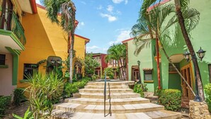 A courtyard with a central staircase surrounded by colorful buildings, palm trees, and stone steps. - Hidden Paradise LS17 -Minutes to All the Action! (Tamarindo)