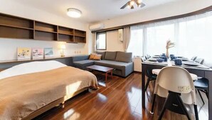 Camera d'albergo con un letto, divano, tavolo da pranzo, sedie e una ventola a soffitto.